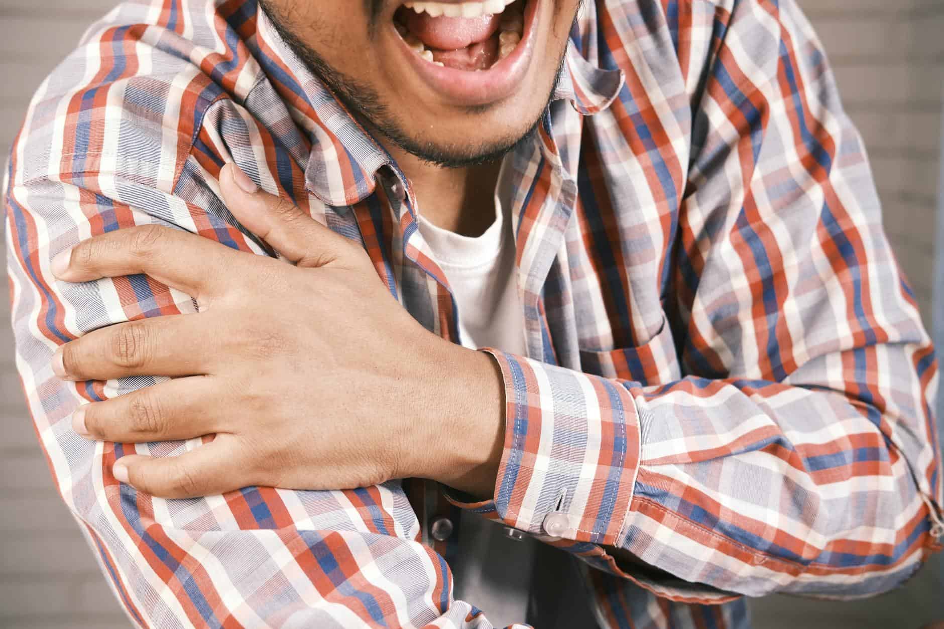 Close-up Photo of a man holding his shoulder