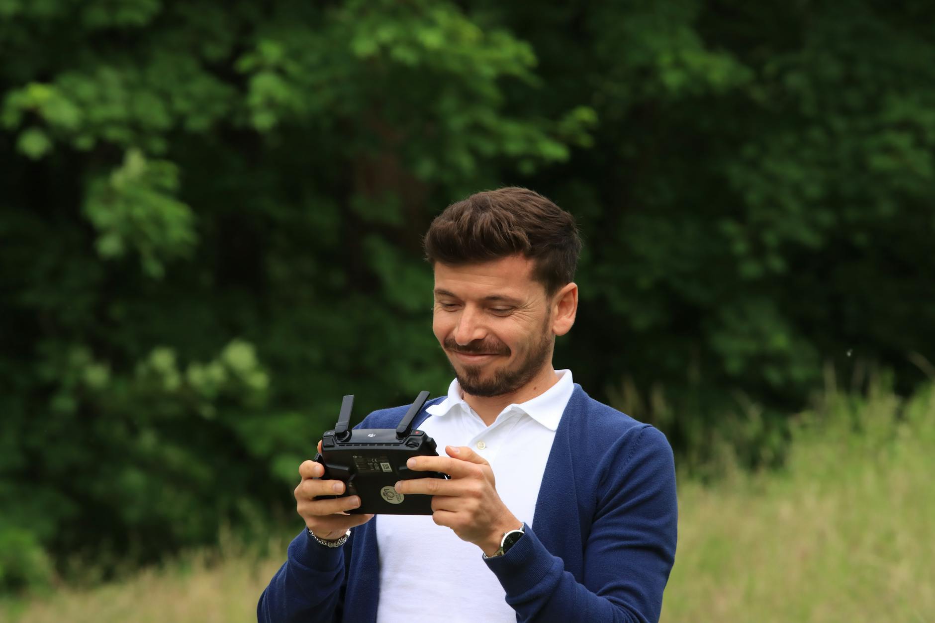 A man is smiling while holding a remote control