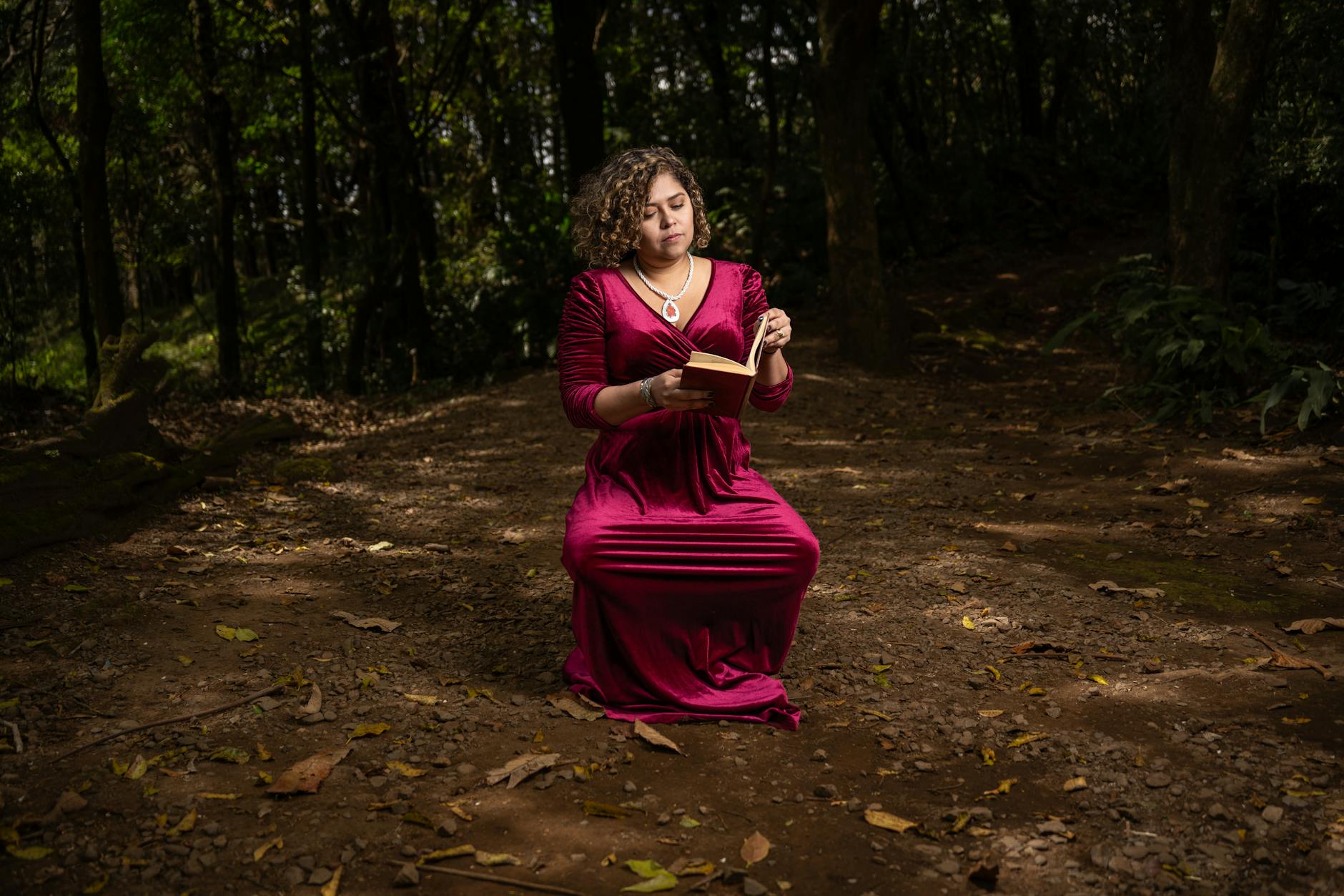 A woman in a red dress kneeling in the woods